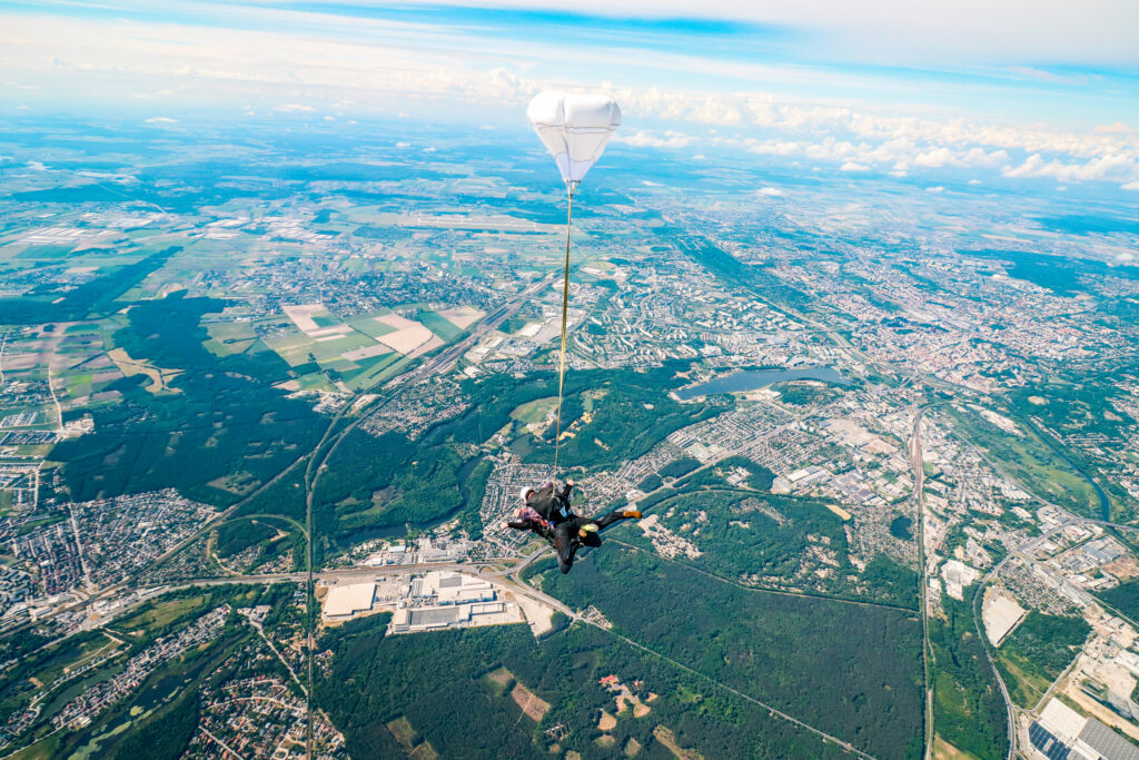 Tandem skydivers under a parachute high above a city