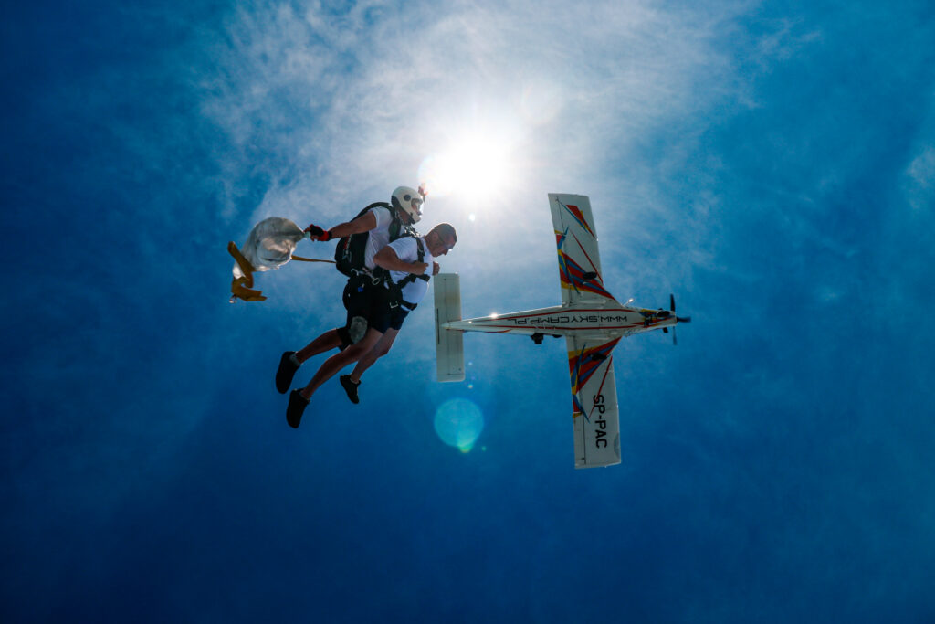 Skydiver falling away from the plane against the sun