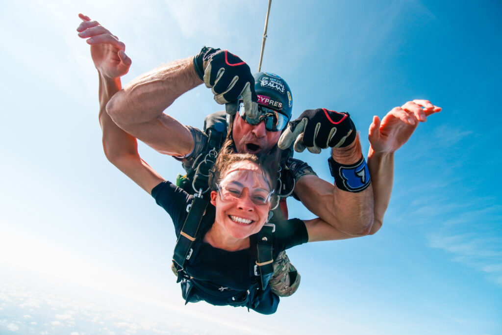 Smiling tandem skydiving passenger in free fall