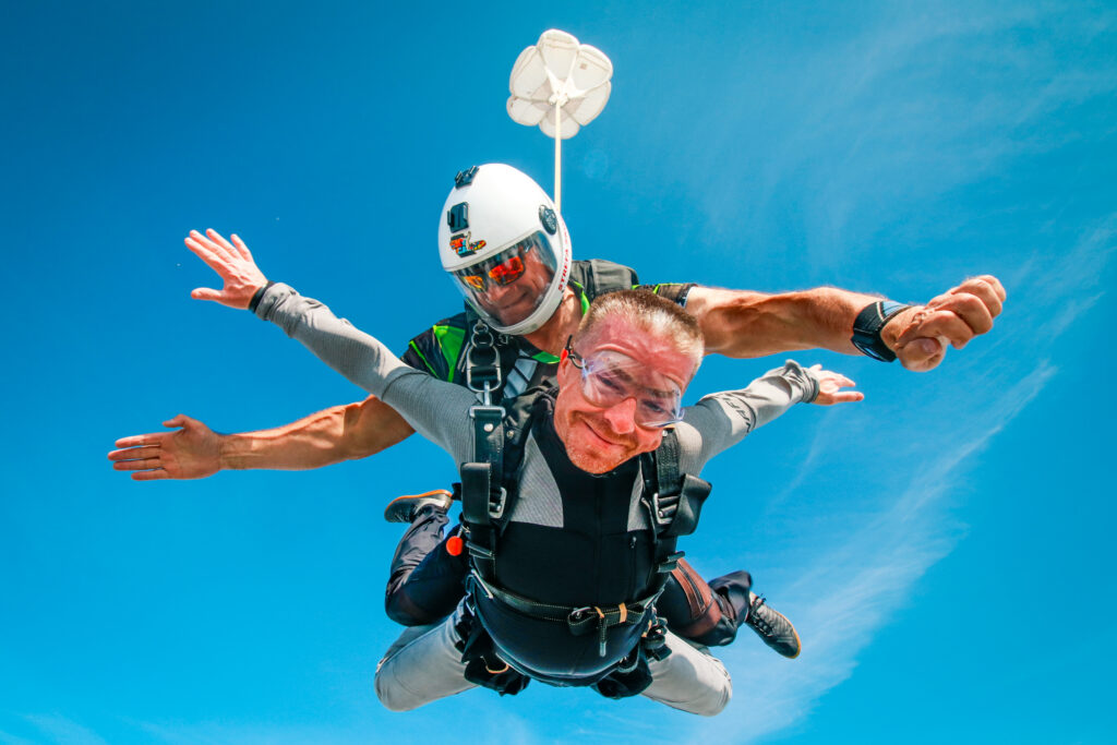 Tandem skydiving passenger with arms spread in free fall