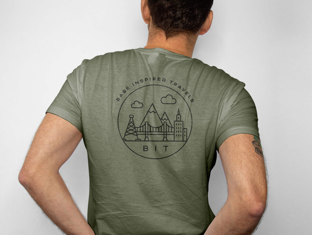 Man seen from behind in an olive T-shirt with the Base Inspired Travels badge