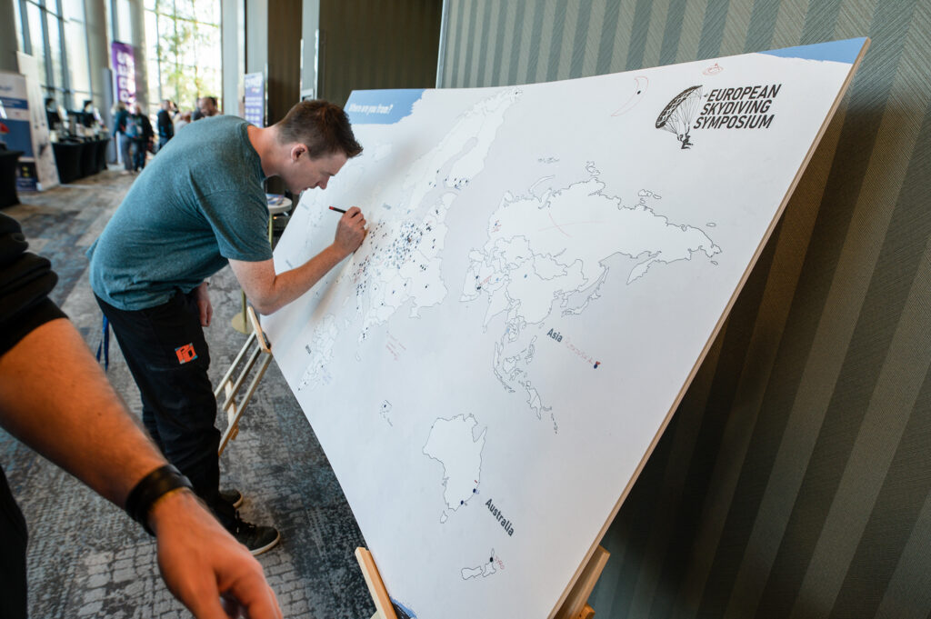 Attendee marking his home on a large world map at the European Skydiving Symposium