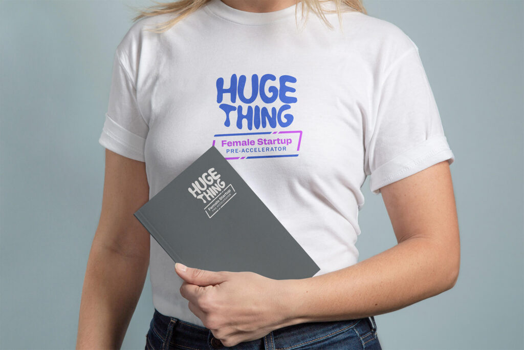 Woman in a Huge Thing Female Startup Pre-Accelerator T-shirt holding a folder