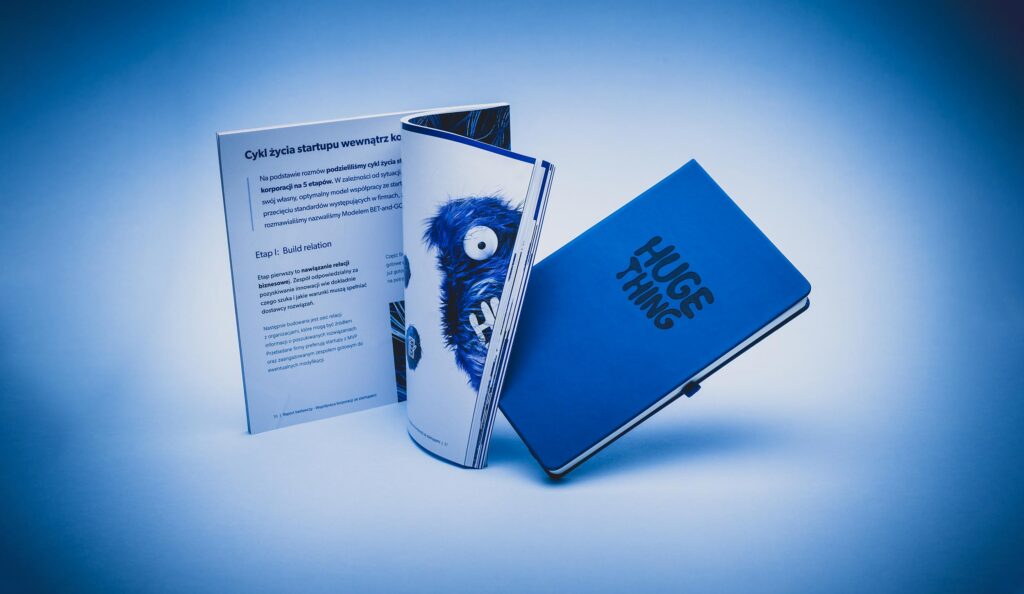 Huge Thing report booklet and notebook on a blue background