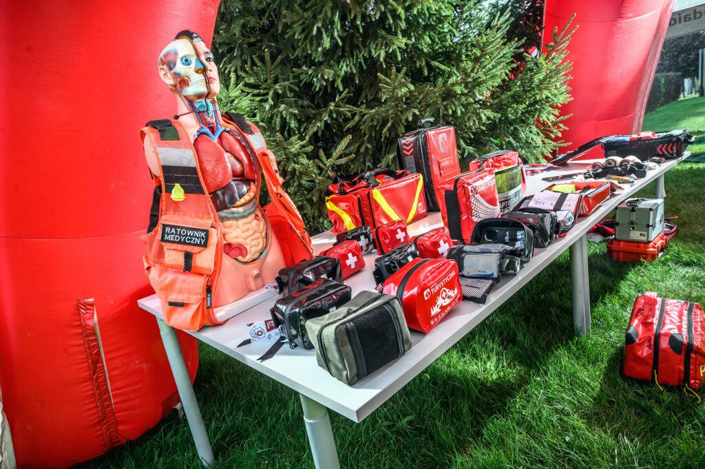 Rescue mannequin and red medical bags on a table at an outdoor event