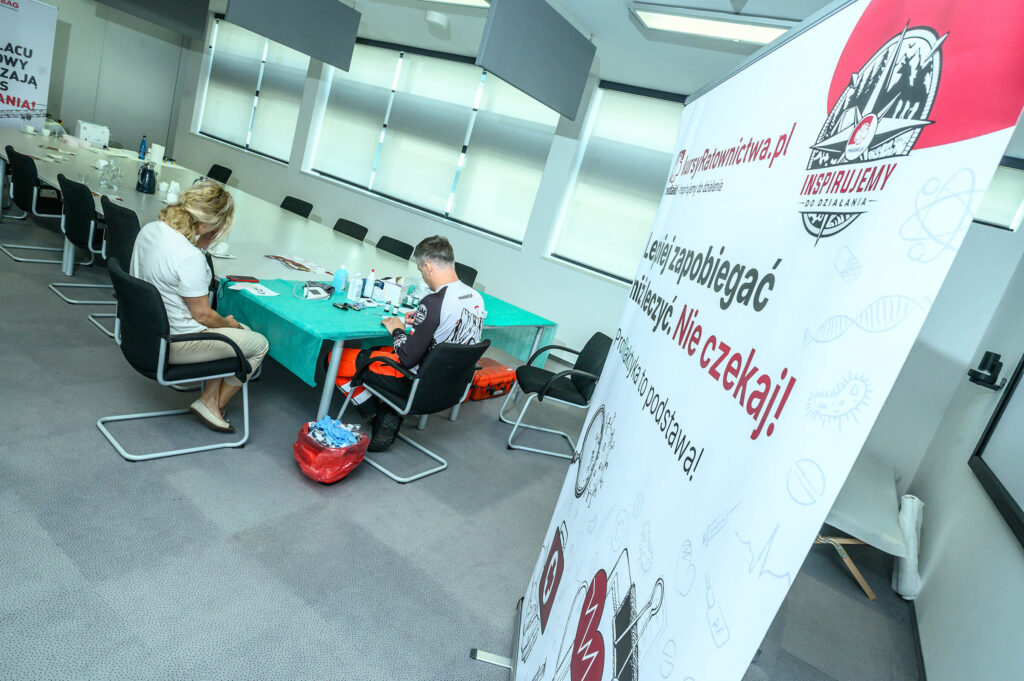 First-aid course participants in a training room with a kursyRatownictwa.pl banner