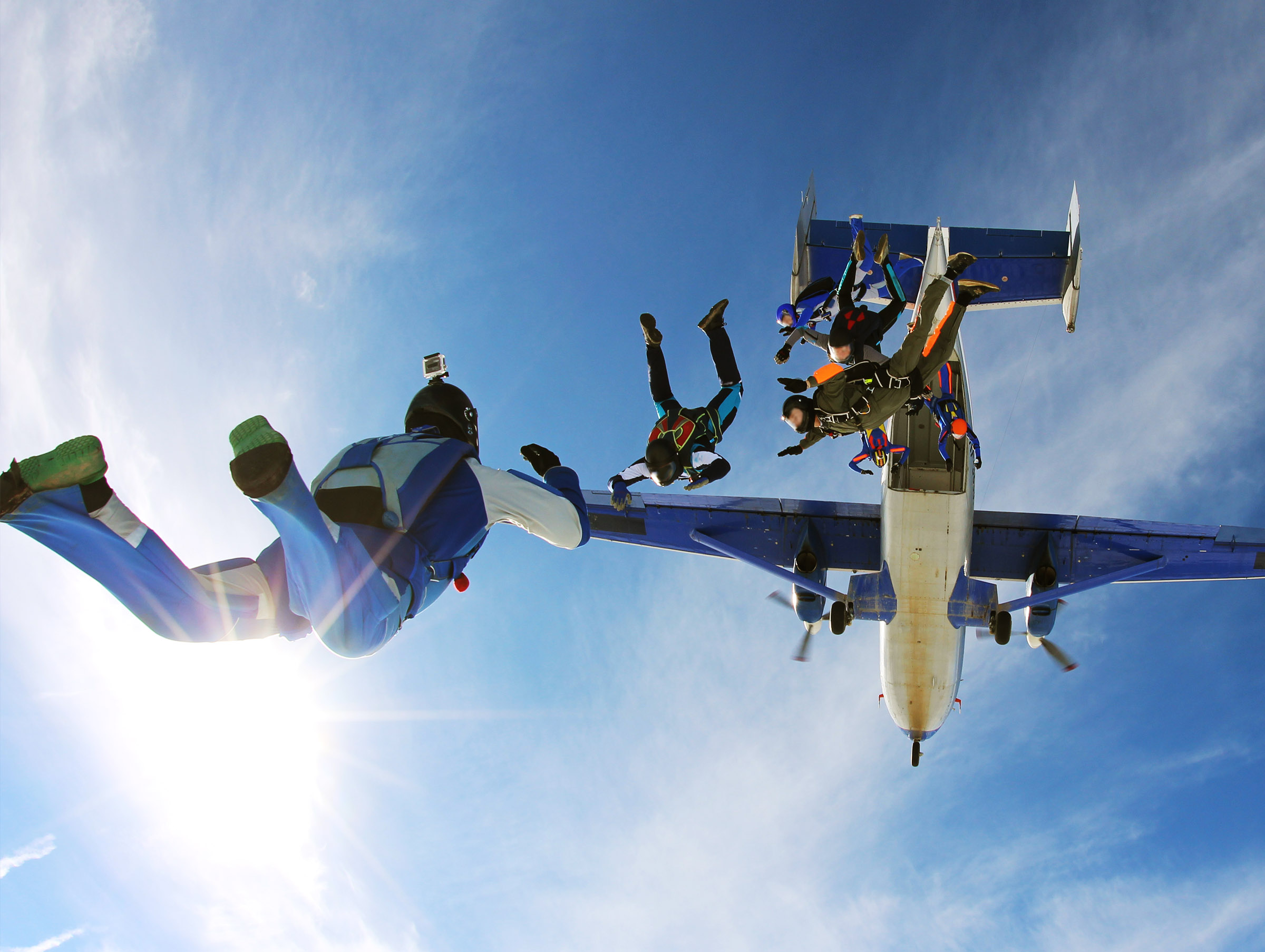 Skydivers leaving a plane against the sun