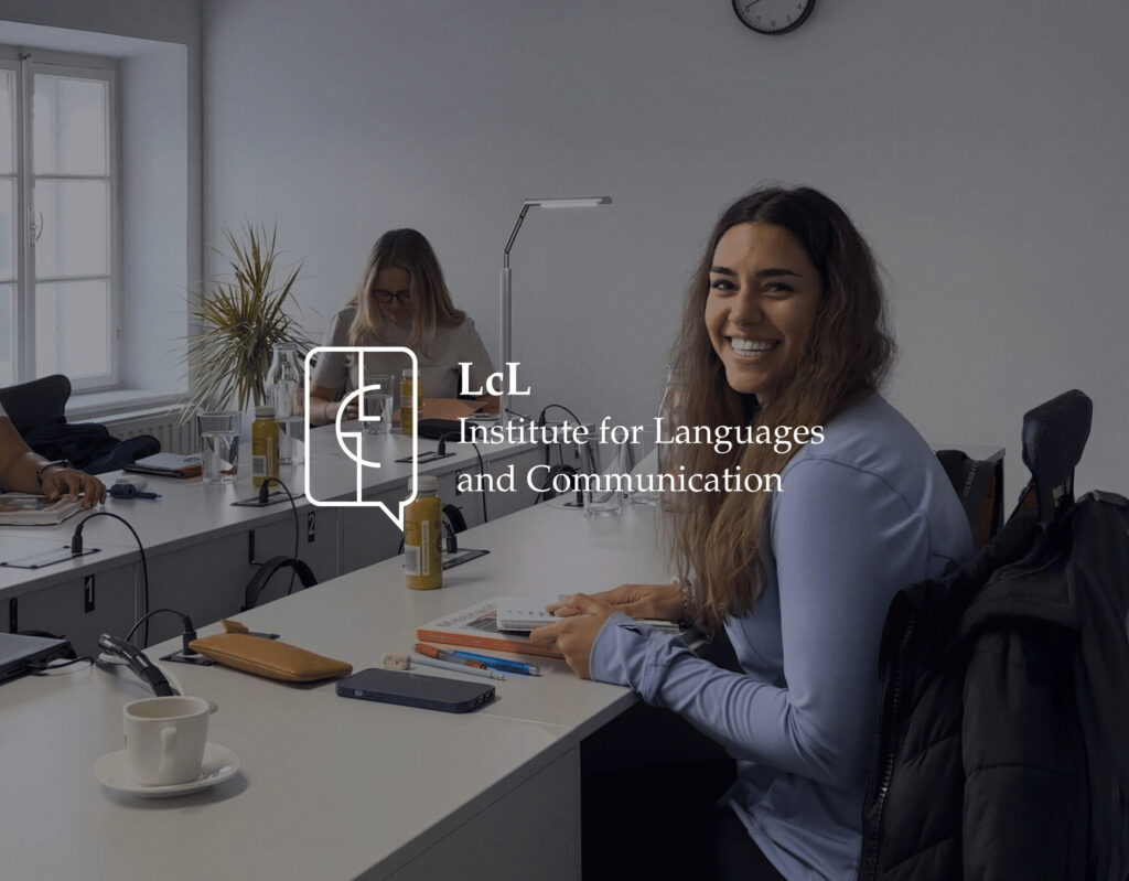 Smiling woman at an office desk, with the LcL Institute for Languages and Communication logo