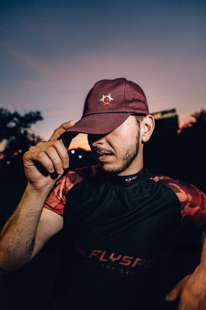 Man wearing a burgundy Flyspot cap at dusk