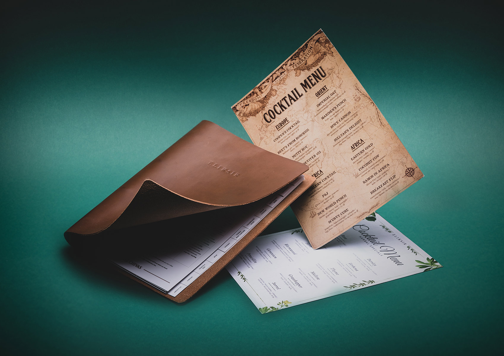 Eliksir cocktail menus in a leather cover on a teal background