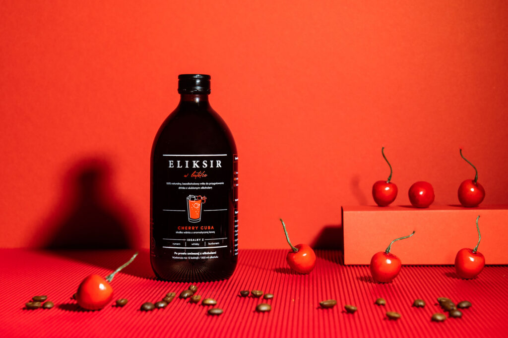 Bottle of Eliksir w butelce with chillies and coffee beans on red