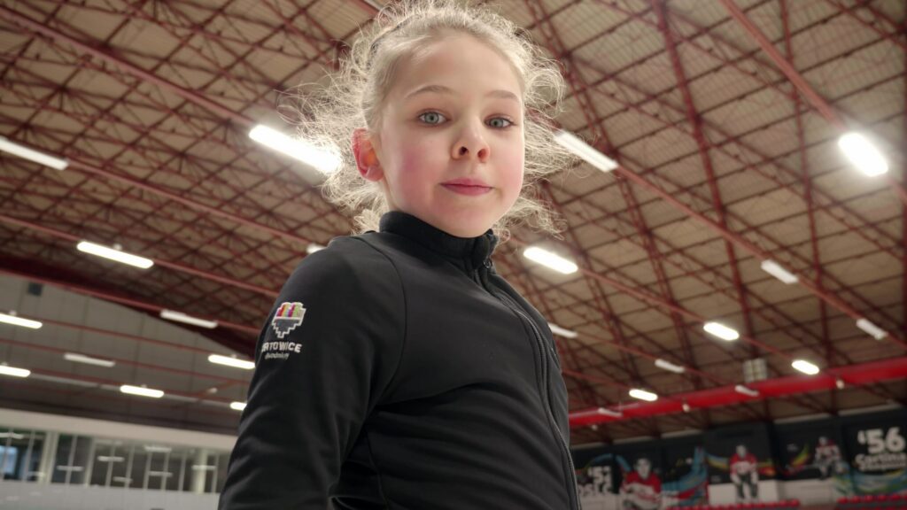 Girl looking into the camera inside a large hall, still from a Flyspot film