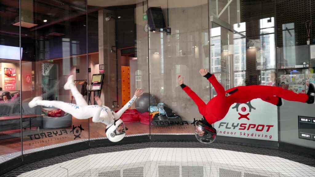 Two flyers in red and white suits inside the Flyspot wind tunnel