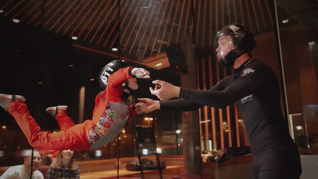 Instructor holding a young flyer in the Flyspot wind tunnel