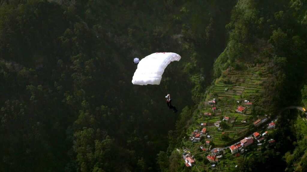 Parachute canopy above a green valley with a village, Madeira