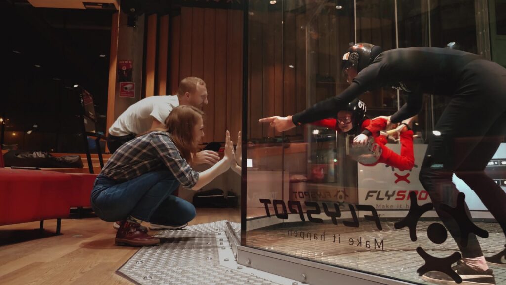 Family watching a child fly through the wind tunnel glass