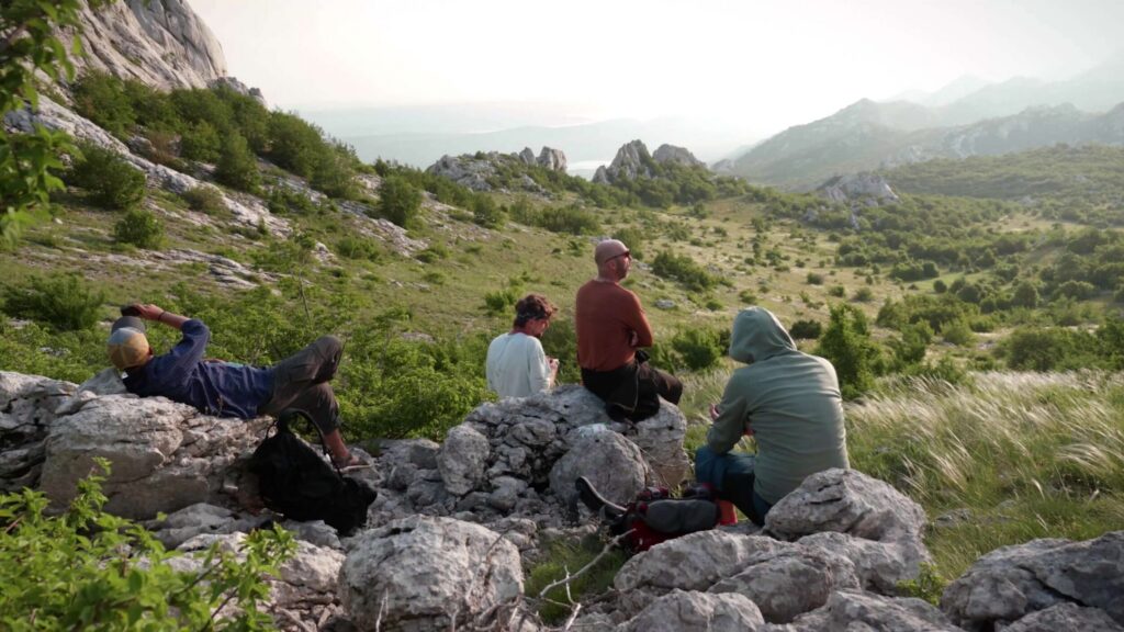 BASE jumpers resting on rocks on a hillside