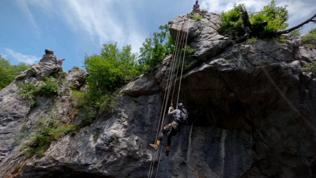 Climbers rappelling down a rock face
