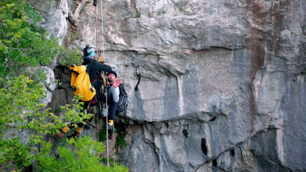 Climber with a yellow bag on a limestone wall