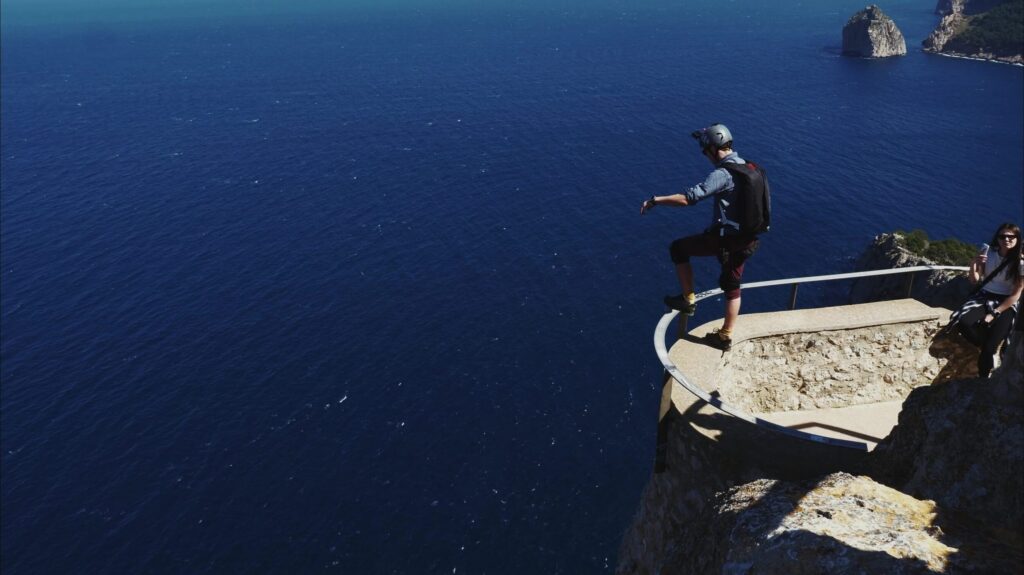 BASE jumper leaping from a ledge high above the sea