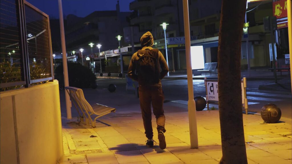 Man walking down a street at night with a BASE rig on his back