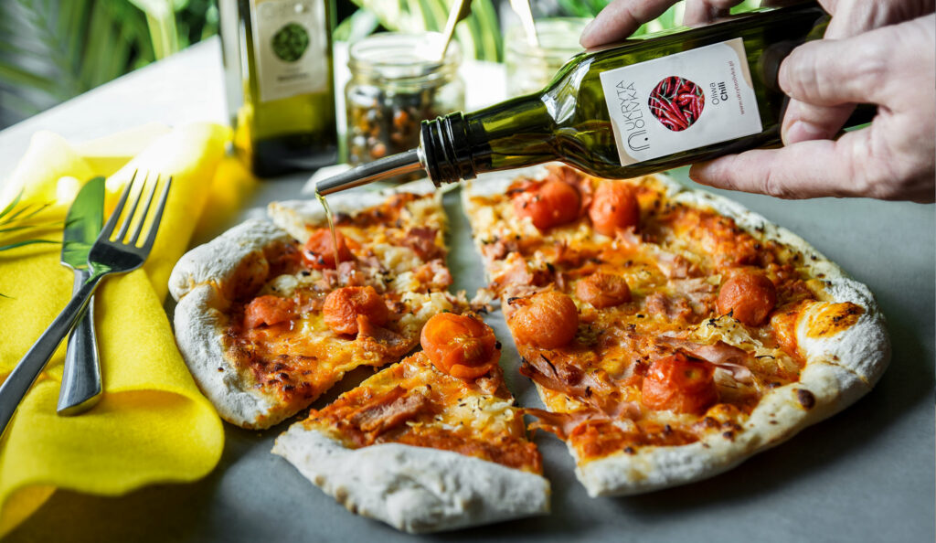 Olive oil being poured over a pizza