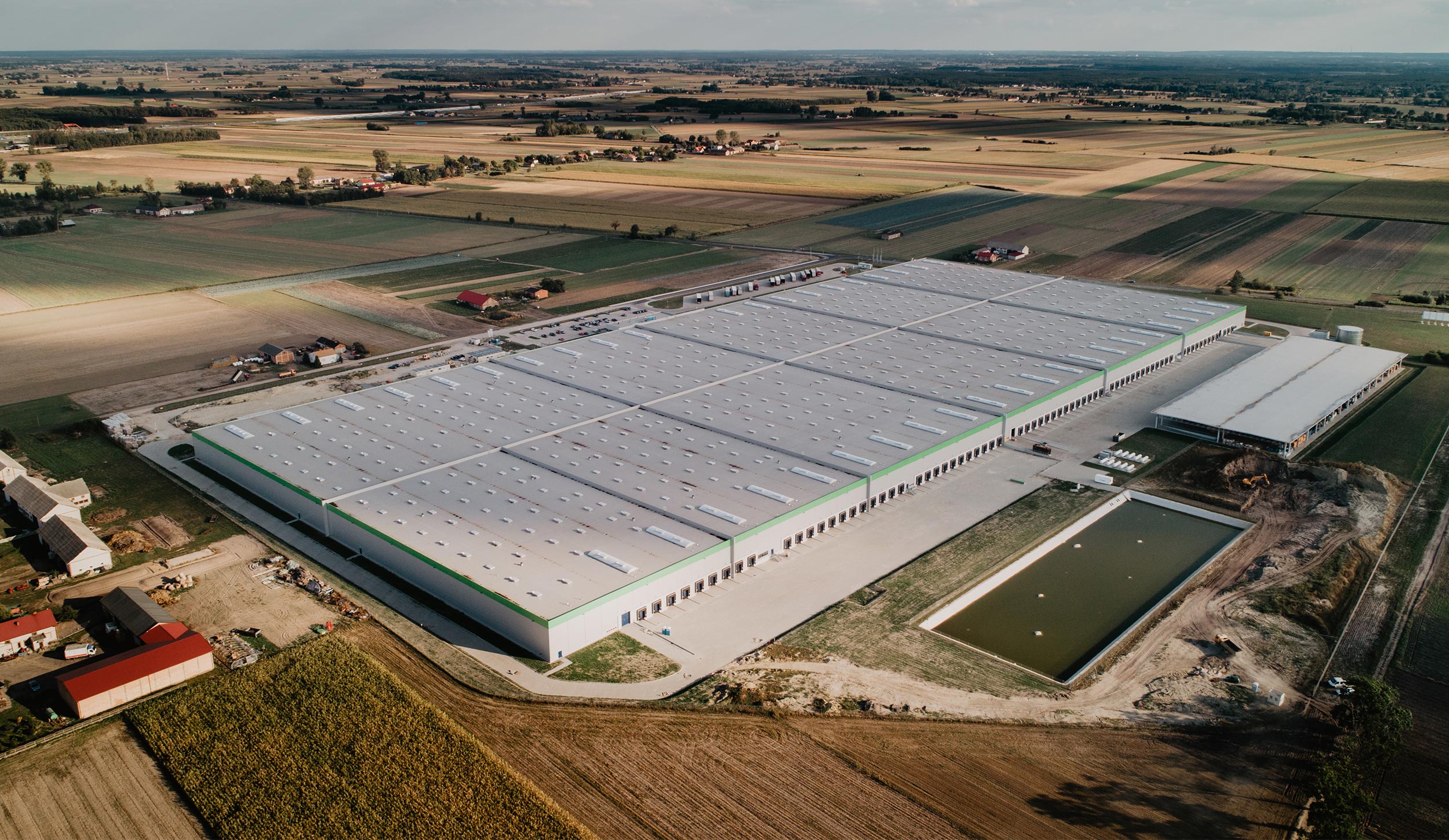 Aerial view of a large warehouse roof surrounded by fields