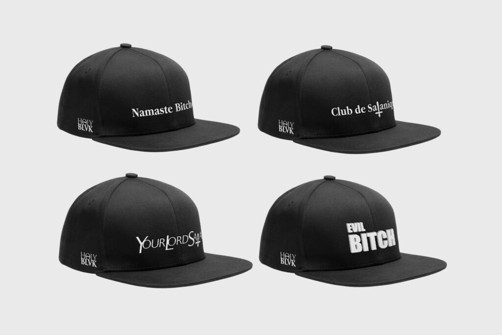 Four black Holy Blvk caps with white text prints